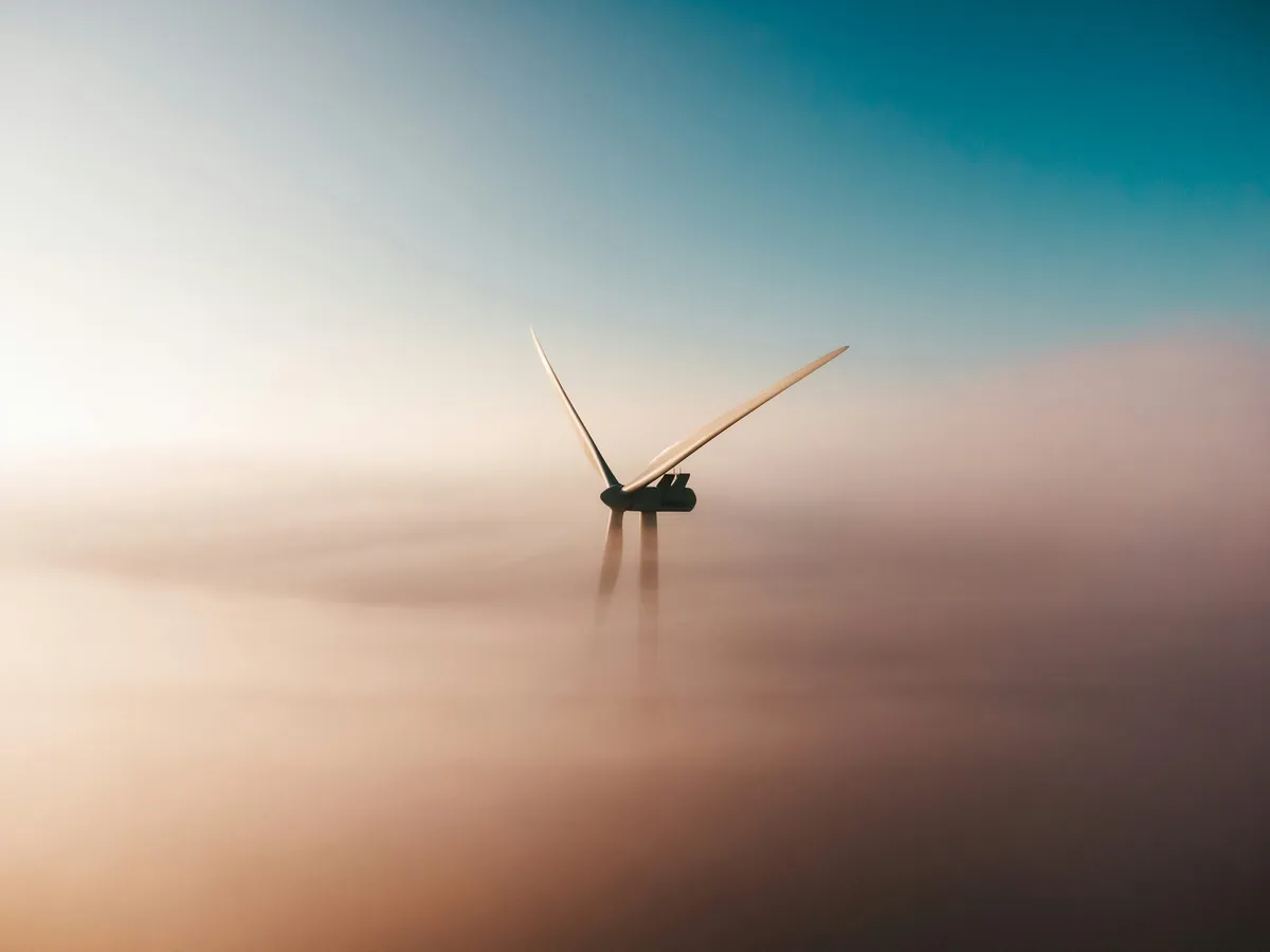A single wind turbine standing in still water under a pale sky