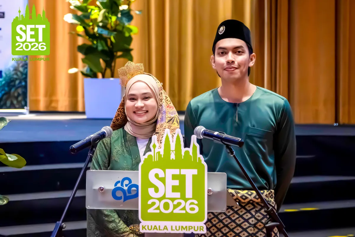 Two hosts in traditional Malaysian dress speaking at the SET2026 lectern in Kuala Lumpur